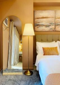 1 dormitorio con cama, lámpara y espejo en Royal Suite linked to Venice with 200mbps Wi-Fi, en Manila
