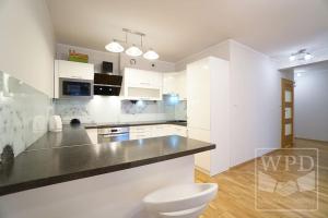 a kitchen with white cabinets and a black counter top at Modern Apartment-City Center-New Building-Garage in Wrocław