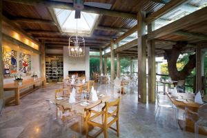 a restaurant with wooden tables and chairs and a fireplace at Kapama Karula in Kapama Private Game Reserve