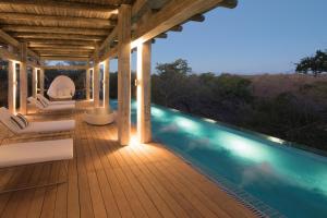 a wooden deck with a swimming pool at night at Kapama Karula in Kapama Private Game Reserve