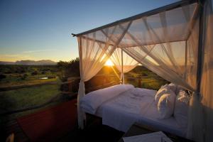 um quarto com uma cama de dossel com o pôr-do-sol ao fundo em Kapama Karula em Kapama Private Game Reserve