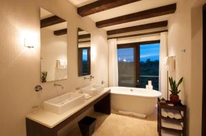 uma casa de banho com 2 lavatórios, uma banheira e uma janela em Kapama River Lodge em Kapama Private Game Reserve