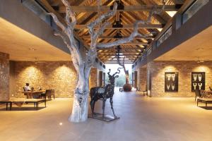 a room with a tree and a statue of a deer at Kapama River Lodge in Kapama Private Game Reserve