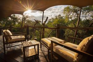 eine Veranda mit einem Tisch, Stühlen und der Sonne in der Unterkunft Kapama Buffalo Camp in Kapama Private Game Reserve