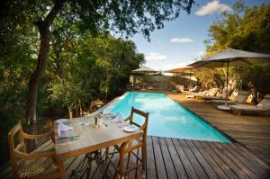 a table and chairs next to a swimming pool at Kapama Buffalo Camp in Kapama Private Game Reserve