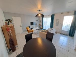 sala de estar con mesa y sofá en - Maison Capucine- Proche centre d'affaire Chauray, Jardin, parking, WIFI et Netflix, idéal voyage d'affaire, familles, ou simple escapade en Chauray