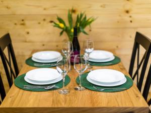 a wooden table with white plates and wine glasses at DOMKI POD ZIELONYM WZGÓRZEM 2 in Kudowa-Zdrój