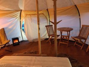 a tent with two chairs and a table and a stove at Terrassen Camping & Cottages in Silkeborg