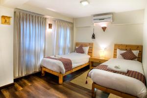 a hotel room with two beds and a window at Hotel Timila in Pātan