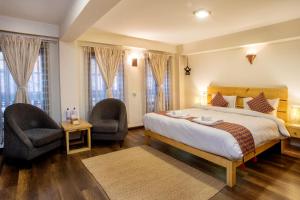 1 Schlafzimmer mit einem großen Bett und 2 Stühlen in der Unterkunft Hotel Timila in Pātan