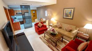 a living room with a couch and red chairs at Xclusive Hotel Apartments in Dubai