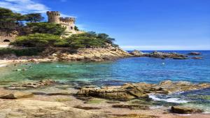 a beach with people in the water and a castle at Catalunya Casas Fun and Frolic in Lloret del Mar 3500 meters to beach! in Lloret de Mar