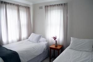 a bedroom with two beds and a vase of flowers on a table at Broadway Self Catering Apartments in Durbanville