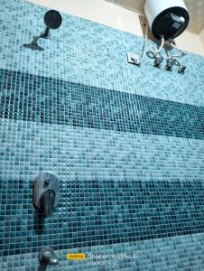 ducha de azulejos azules con cabezal de ducha en Relax Square & Hotel By WB Inn, en Alwar