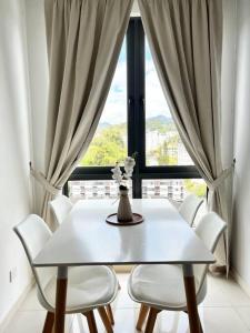 a white dining room table with white chairs and a window at Lily Ville in Tanah Rata