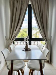 a white table and chairs in a room with a window at Lily Ville in Tanah Rata