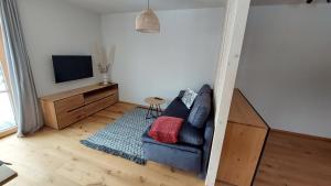 a living room with a blue couch and a tv at Ferienwohnung Ida in Lofer
