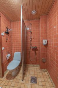 La salle de bains est pourvue de carrelage rouge, de toilettes et d'une douche. dans l'établissement Tahko-Tours Oy, à Tahkovuori