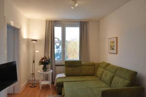 een woonkamer met een groene bank en een televisie bij Appartementhaus Flori in Timmendorfer Strand