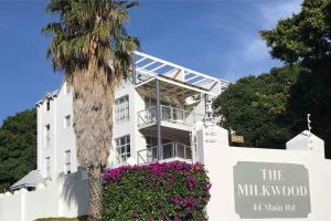 a palm tree in front of a white building with flowers at Chapman`s Peak, Loft mit Sea-und Mountainview in Hout Bay