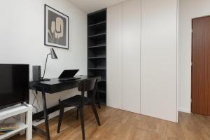 a room with a desk with a computer and a closet at Modern Studio with Balcony Warsaw Mokotów by Renters in Warsaw