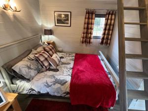 Luxury Woodland Lodge في نيوبورت باجنل: غرفة نوم بسرير وبطانية حمراء
