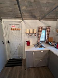 a kitchen with a white door and a sink at Luxury Woodland Lodge in Newport Pagnell