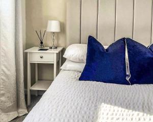 a bed with a blue pillow and a side table at 3-Bed House in London Garden & free parking in Dartford