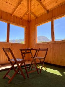 uma mesa e duas cadeiras num quarto com janelas em Cabañas Rio Pangal em Puerto Aisén