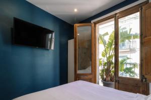 1 dormitorio con pared azul, cama y TV en Hostal Sol y K, en Barcelona
