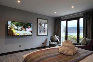 a bedroom with a large bed with a tv on the wall at The Beach House Loch Lomond in Luss