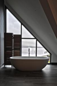 a large bath tub in a room with a large window at The Beach House Loch Lomond in Luss