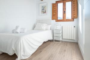 um quarto branco com uma cama e uma janela em Casa Rafa em Buellas