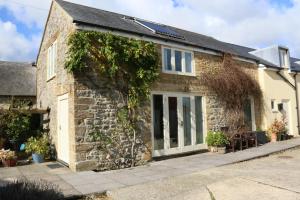 an old stone house with glass doors at The Old Milking Parlour at Knapp Farm in Dorchester
