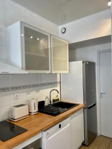 eine Küche mit weißen Schränken, einer Spüle und einem Kühlschrank in der Unterkunft Appartement à louer, Bandol in Bandol