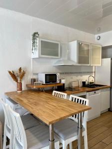 eine Küche mit einem Holztisch und weißen Stühlen in der Unterkunft Appartement à louer, Bandol in Bandol