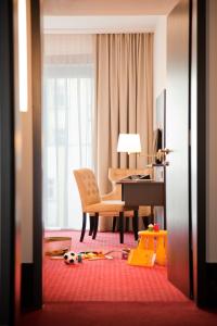 a living room with a table and a chair and a desk at Gold Palais Hotel in Berlin
