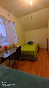 1 dormitorio con cama verde y escritorio en Casita de Sara, en Castro