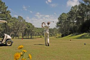 a man swinging a golf club in a field at Casa Dash Beach Houses in Punta del Este