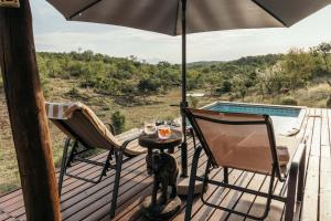 a dog sitting on a deck with a table and an umbrella at Isambane Camp in Balule Game Reserve