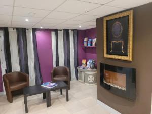 una sala de espera con mesa, sillas y paredes púrpuras en Hôtel Le Cosy Blois Villebarou, en Blois