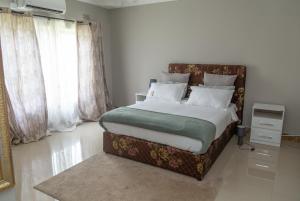 a bedroom with a large bed and a large window at Muka Staytel in Ndola