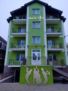 un bâtiment vert avec un panneau qui lit magico dans l'établissement Апарт-отель "МАЭСТРО", à Anapa