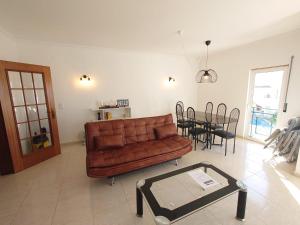 - un salon avec un canapé en cuir brun et une table dans l'établissement Apartamento Mimosas, à Albufeira