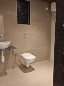 a bathroom with a toilet and a sink at Sk Resort in Alibaug