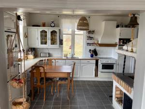 cocina con armarios blancos y mesa de madera en Grellsbo en Grebbestad