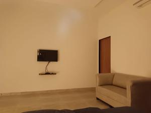 sala de estar con sofá y TV en la pared en Sk Resort en Alibaug