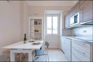 a white kitchen with a white table and a bottle of wine at Appartamento Toscanella in Florence