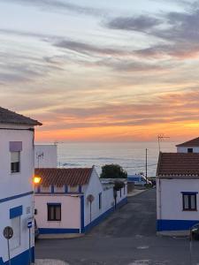 eine Reihe von Gebäuden mit dem Ozean im Hintergrund in der Unterkunft Casa dos Buizinhos in Porto Covo