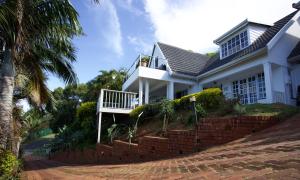 a white house with a porch and a brick wall at Shelbourne Lodge in Durban